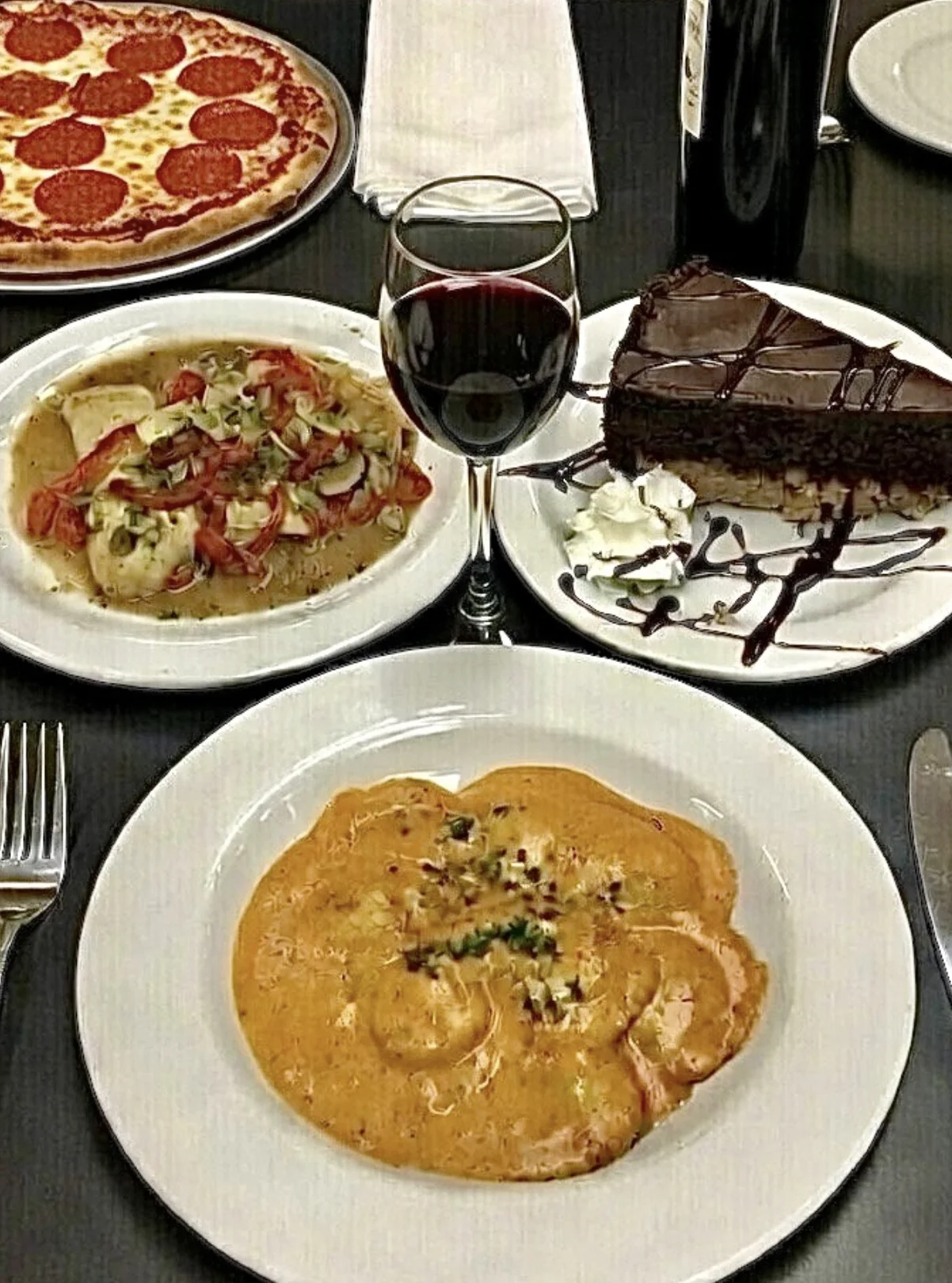 An Italian dinner spread with chicken, dessert, pizza, and wine