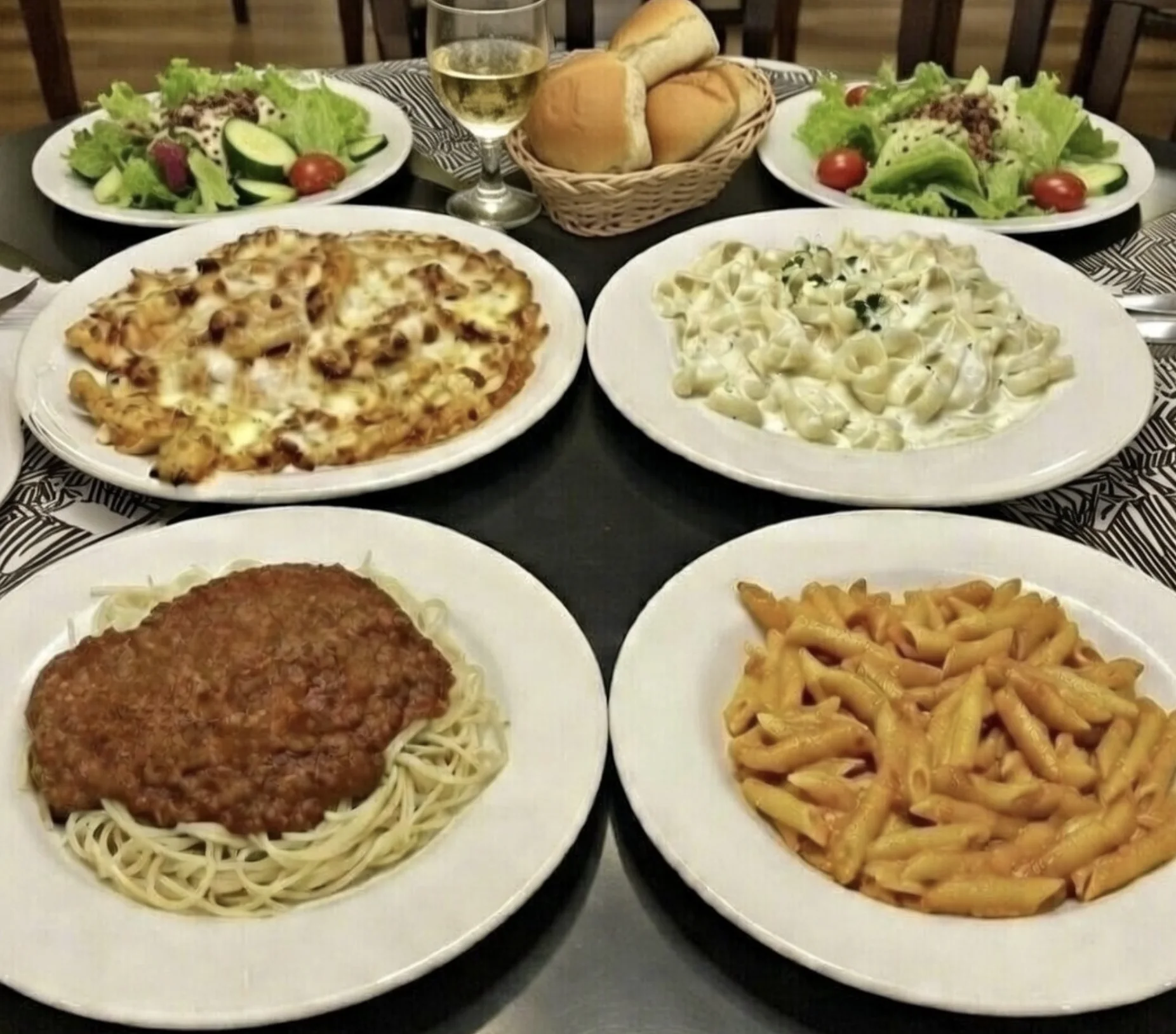 A table filled with Mama Teresa's pasta dishes, salads, bread, and wine